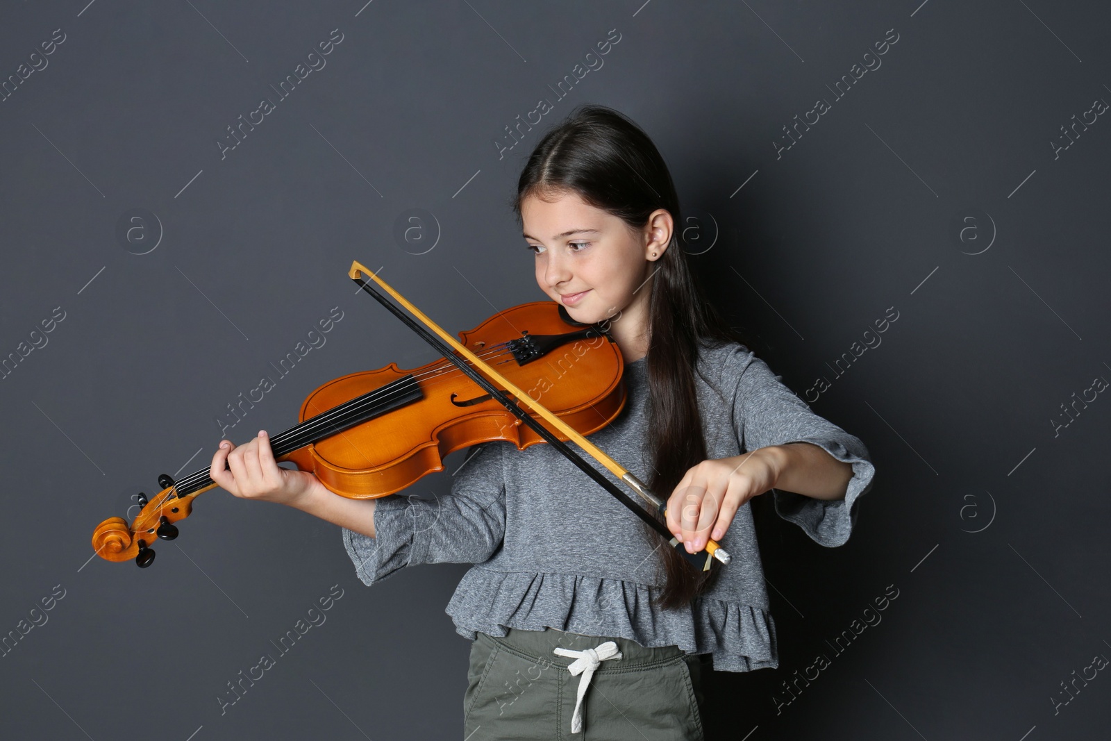 Photo of Preteen girl playing violin on black background