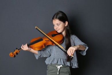 Photo of Preteen girl playing violin on black background