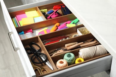 Sewing accessories and stationery in open desk drawer indoors