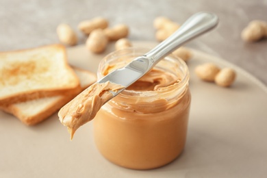 Photo of Jar and knife with creamy peanut butter on table