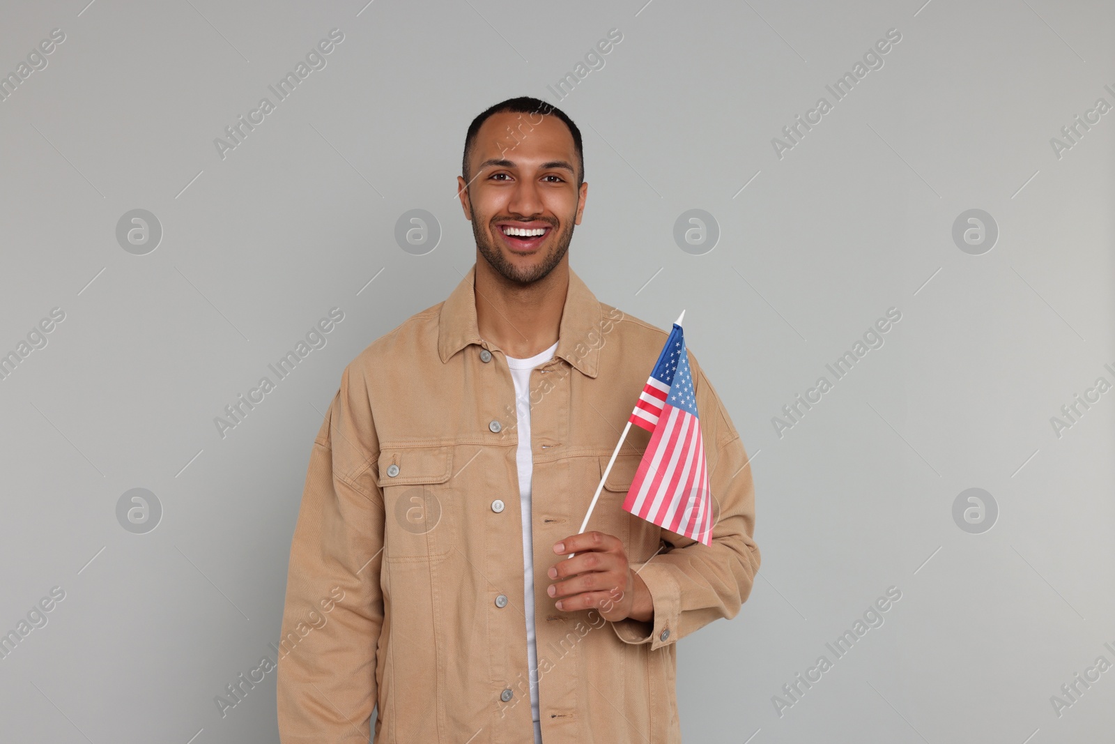 Photo of 4th of July - Independence Day of USA. Happy man with American flag on light grey background, space for text