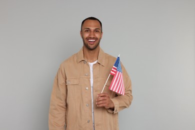 4th of July - Independence Day of USA. Happy man with American flag on light grey background, space for text