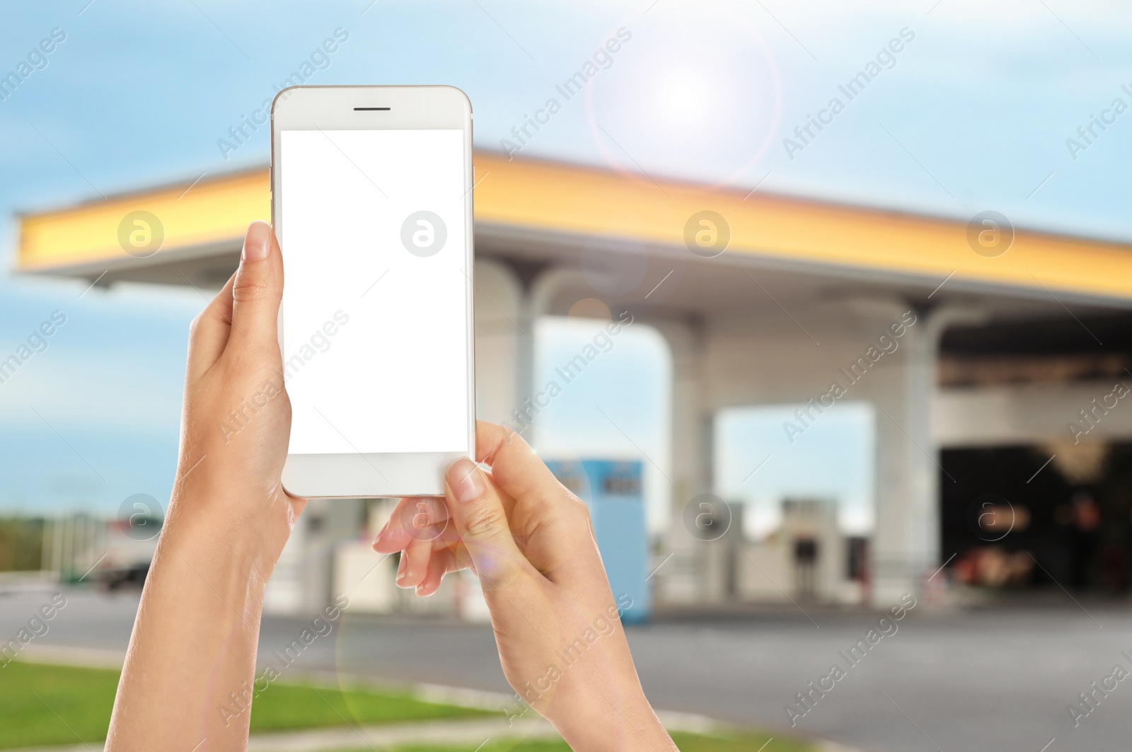 Image of Woman paying for refueling via smartphone at gas station, closeup. Device with empty screen