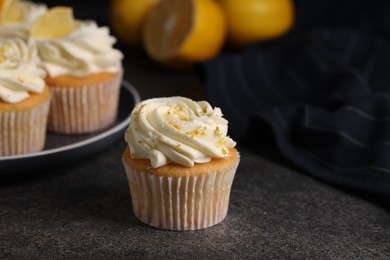 Delicious cupcake with white cream and lemon zest on gray table, closeup