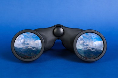 Image of Binoculars on blue background. Mountain landscape reflecting in lenses