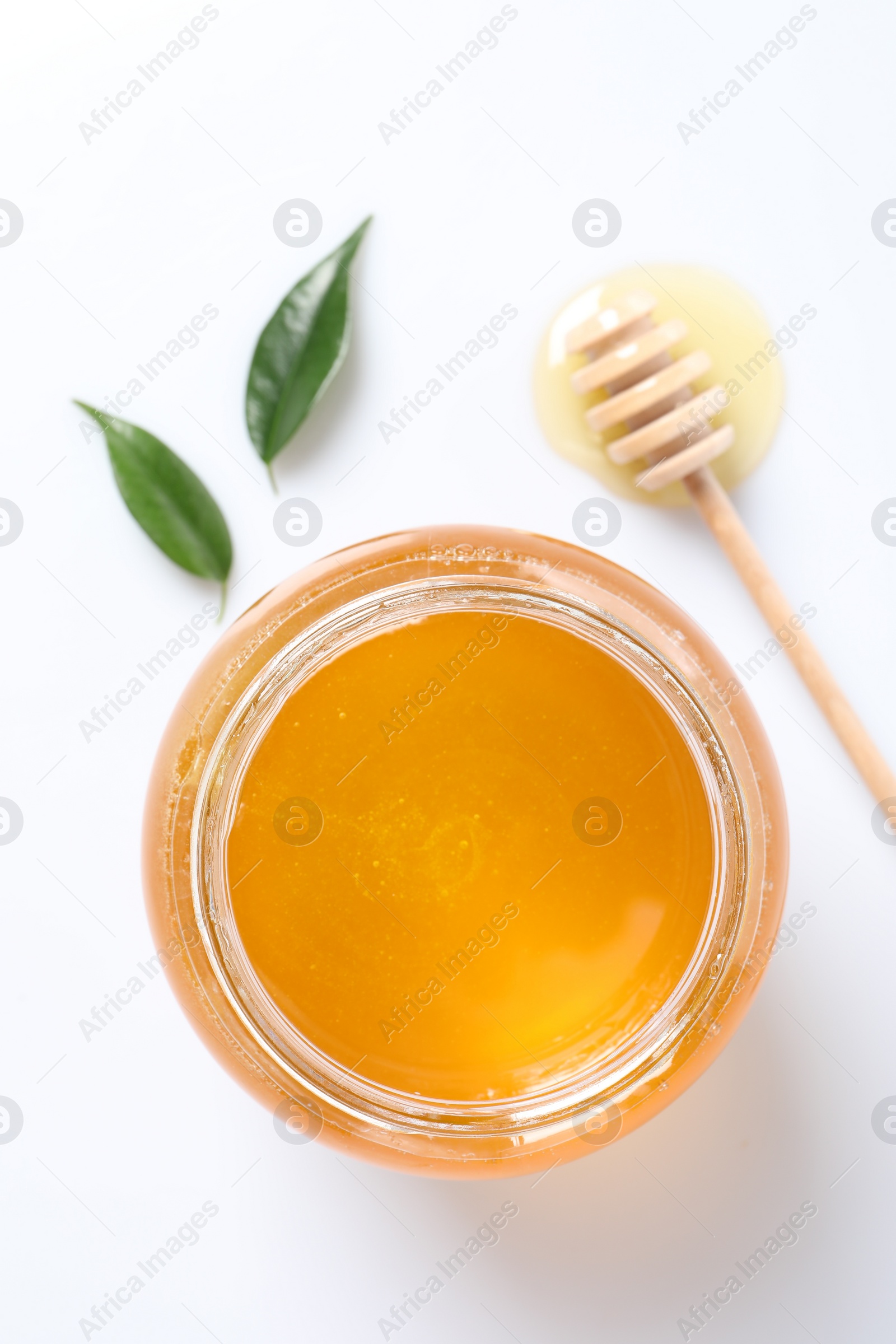 Photo of Tasty honey in glass jar, dipper and leaves isolated on white, top view