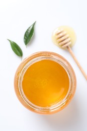 Photo of Tasty honey in glass jar, dipper and leaves isolated on white, top view