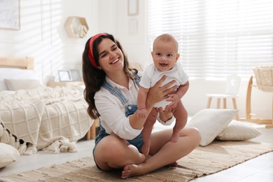 Happy young mother with her cute baby on floor in bedroom