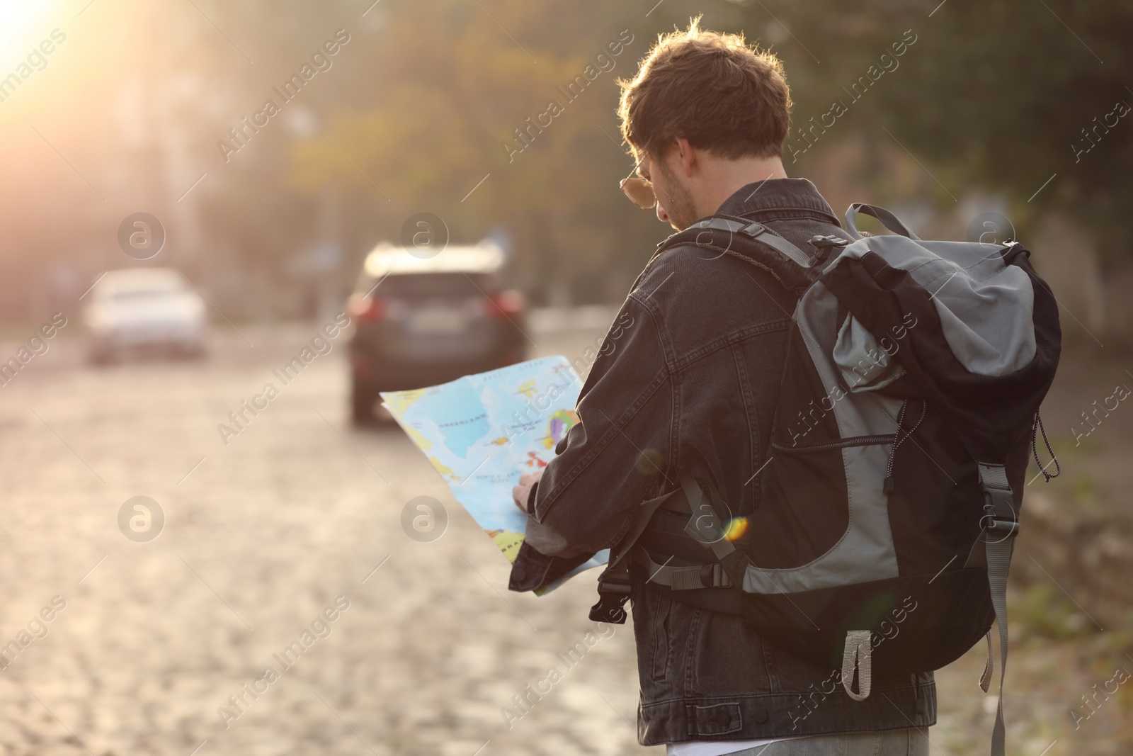 Photo of Traveler with world map on city street, back view