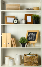 White shelving unit with photo frames and different decorative elements