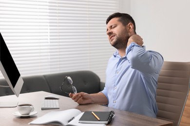 Photo of Man suffering from neck pain in office