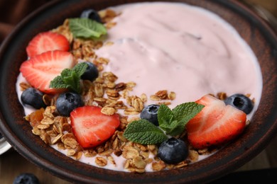 Bowl with yogurt, berries and granola on table, closeup