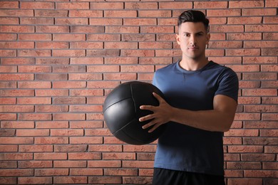 Photo of Athletic man with medicine ball near red brick wall