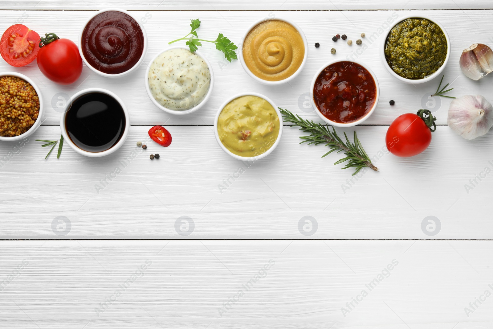 Photo of Many different sauces, spices and vegetables on white wooden table, flat lay. Space for text