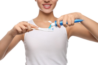 Photo of Woman applying toothpaste on brush against white background, closeup