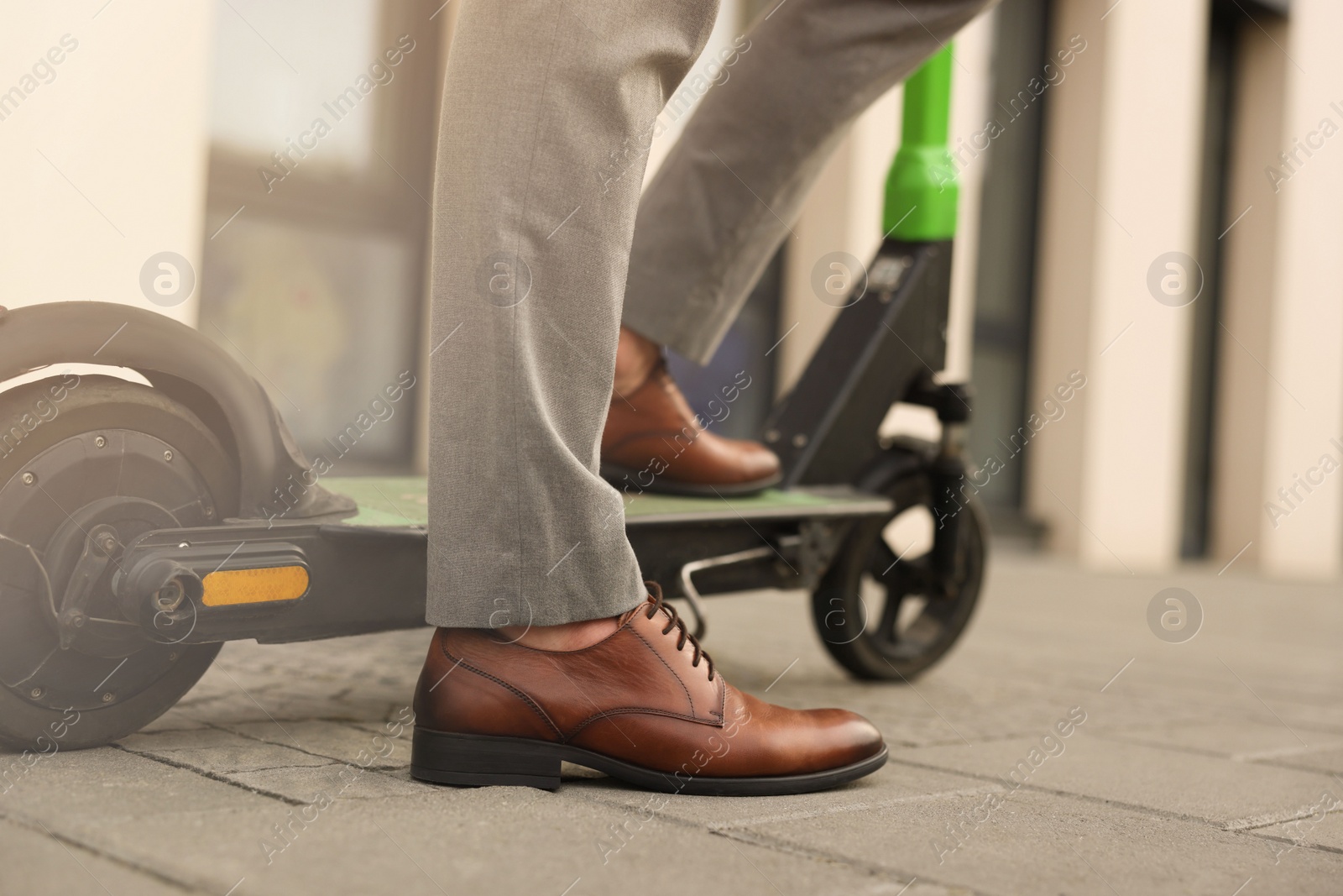 Photo of Businessman with modern kick scooter on city street, closeup