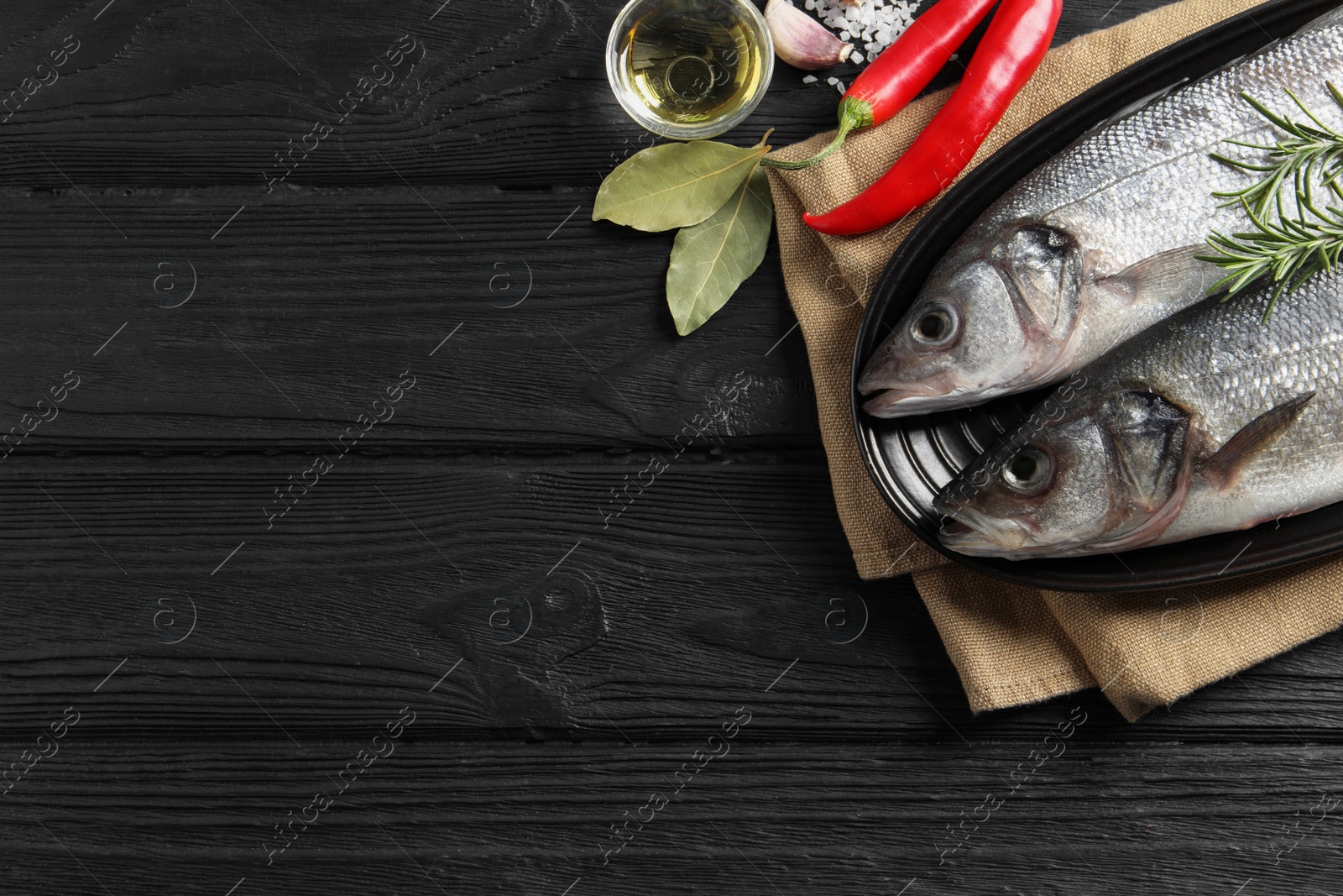 Photo of Flat lay composition with tasty sea bass fish on black wooden table. Space for text