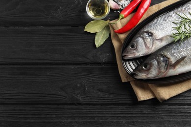 Photo of Flat lay composition with tasty sea bass fish on black wooden table. Space for text