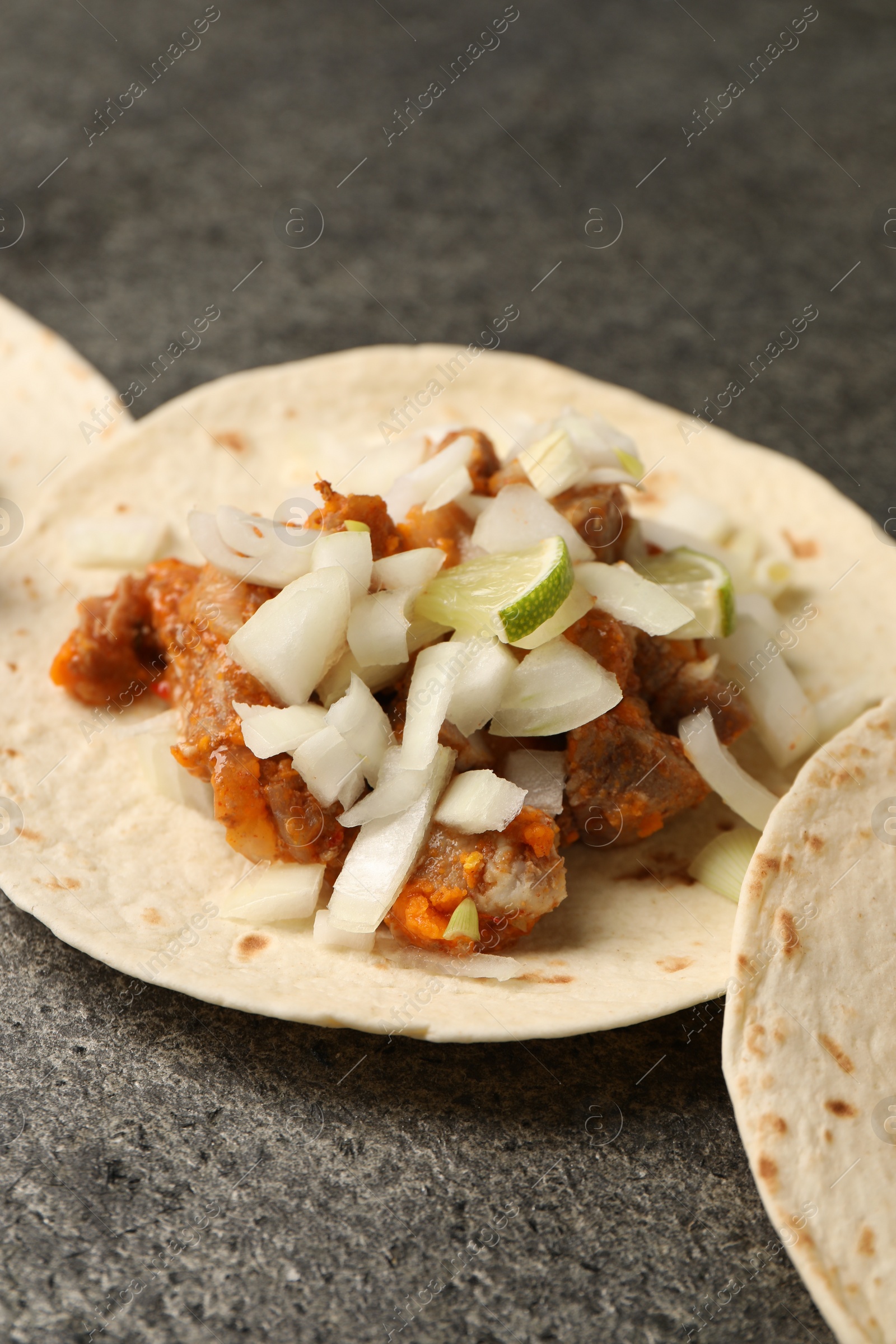 Photo of Delicious tacos with vegetables, meat and lime on grey textured table, closeup