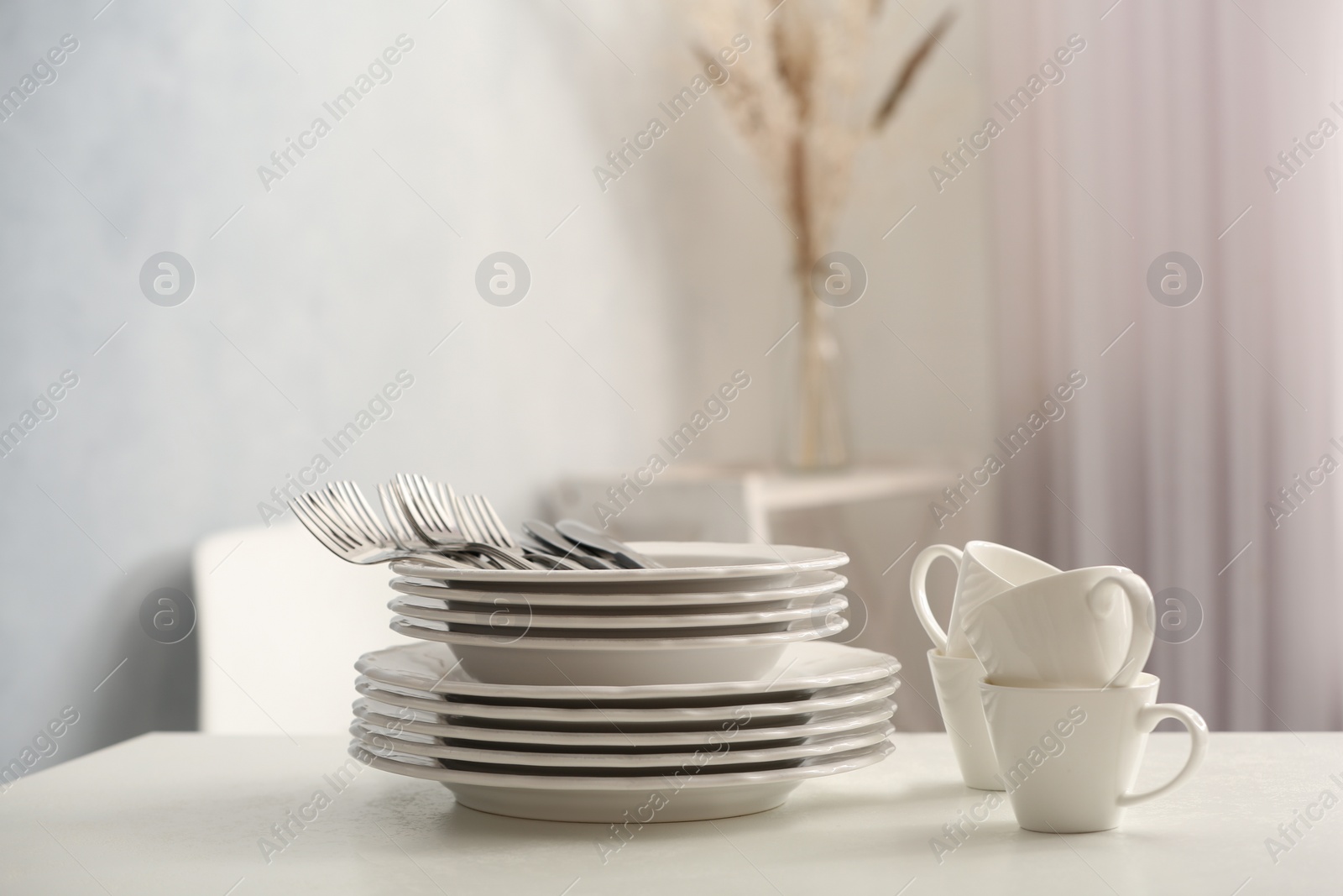 Photo of Set of clean dishware and cutlery on white table indoors. Space for text