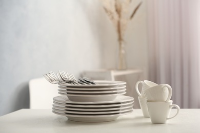 Set of clean dishware and cutlery on white table indoors. Space for text