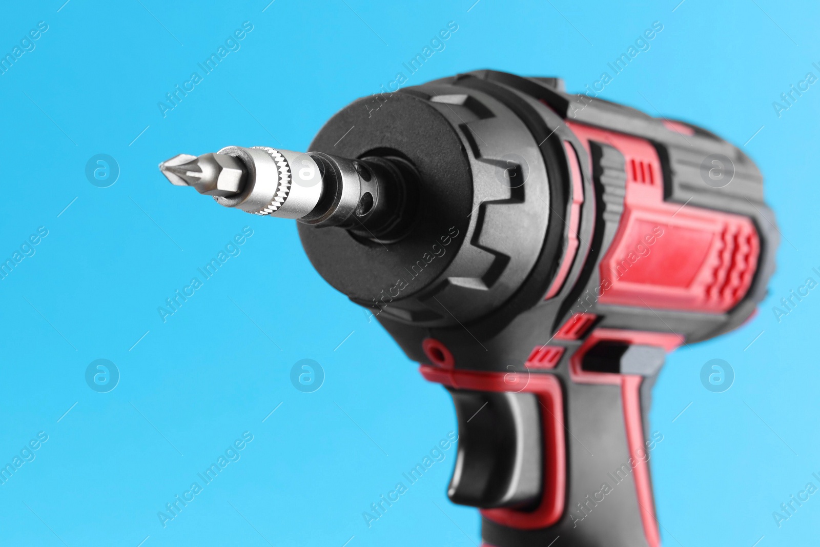 Photo of Modern electric screwdriver on light blue background, closeup. Space for text