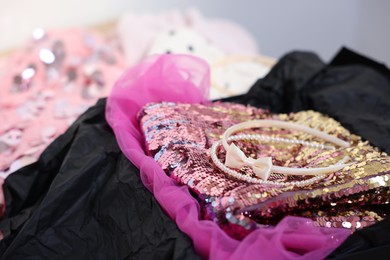 Photo of Headbands and stylish pink carnival costume with sequins in black box, closeup