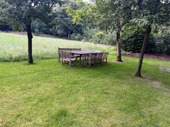 Wooden table with bench and chairs in garden. Landscape design