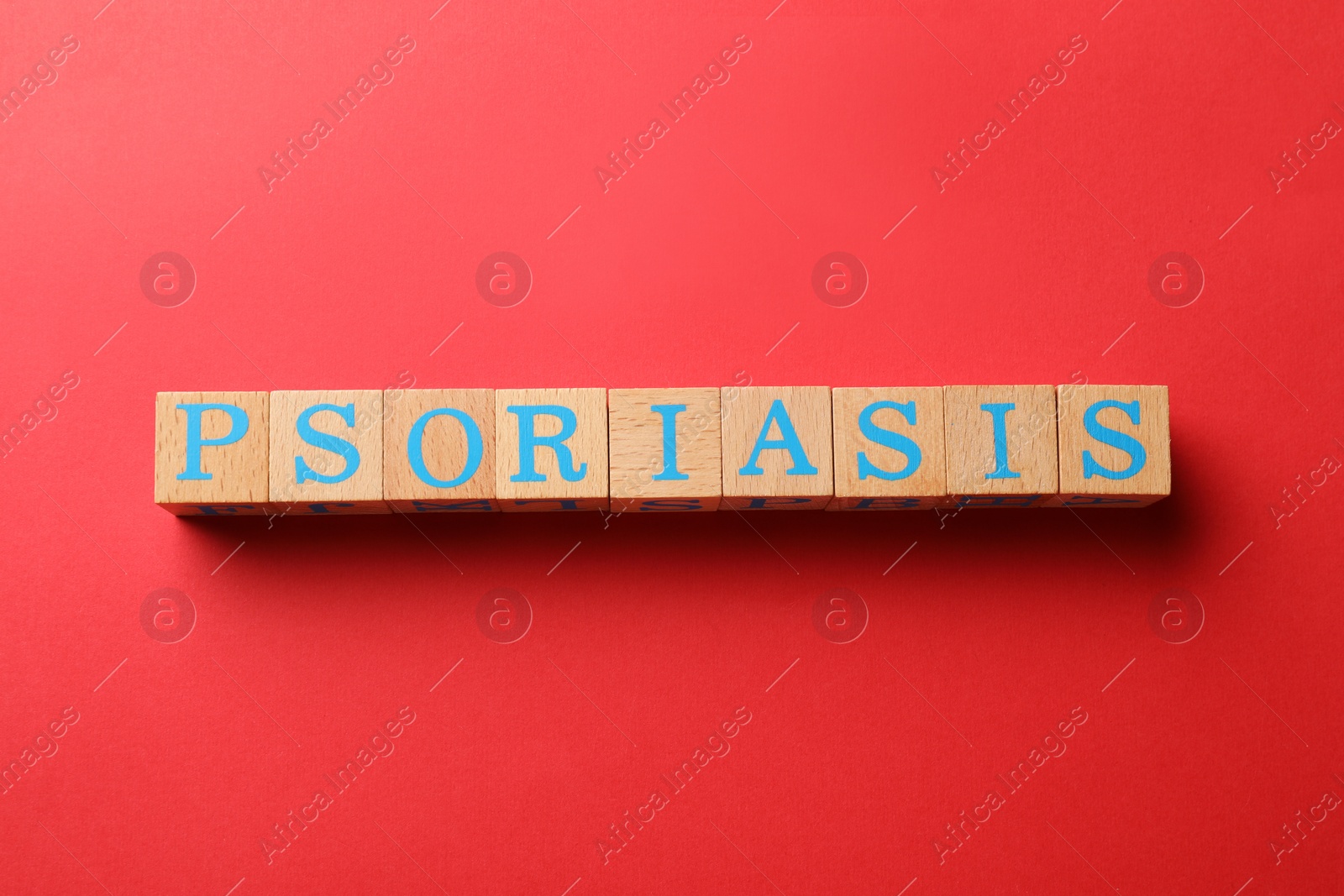 Photo of Word Psoriasis made of wooden cubes with letters on red background, top view