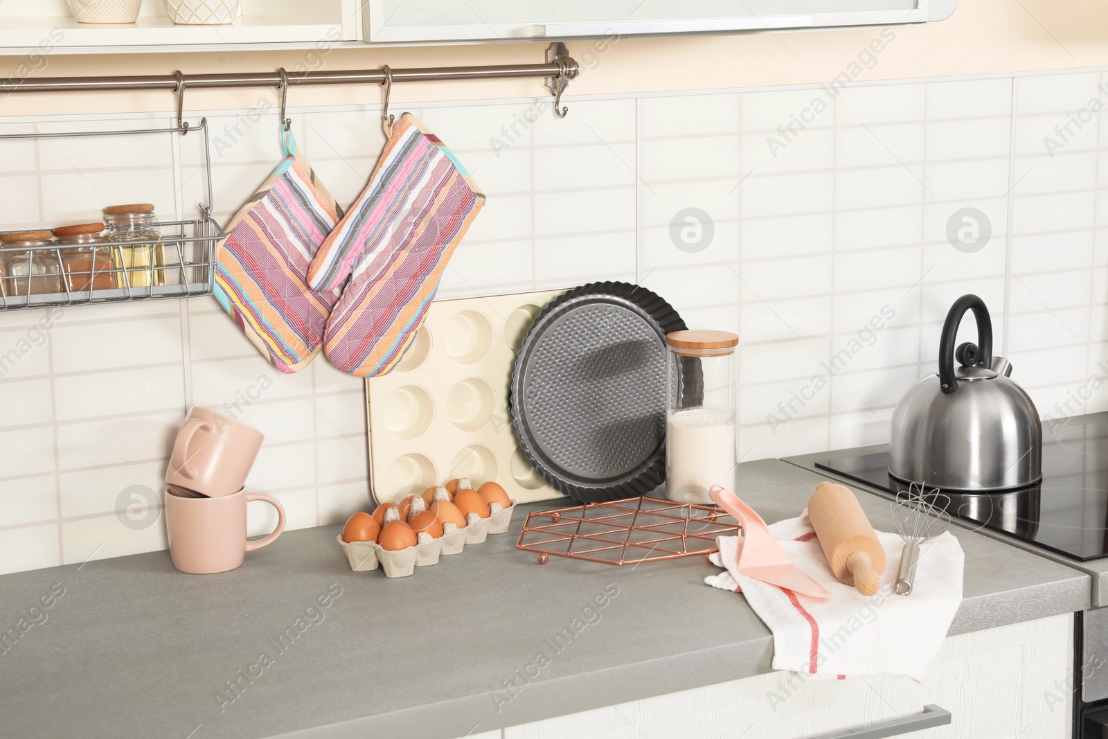 Photo of Set of clean cookware, utensils and products on table in modern kitchen