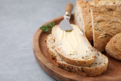 Tasty bread with butter and knife on grey table, closeup. Space for text