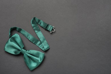 Photo of Stylish green satin bow tie on dark background, top view. Space for text