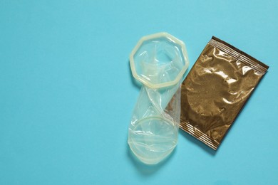 Unrolled female condom and package on light blue background, flat lay with space for text. Safe sex