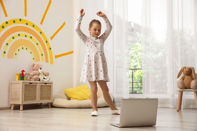 Cute little girl taking online dance class at home