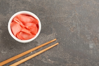 Spicy pickled ginger and chopsticks on grey table, flat lay. Space for text