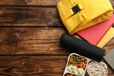 Photo of Flat lay composition with thermos and lunch box on wooden background, space for text