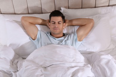 Photo of Man sleeping in comfortable bed with white linens, above view
