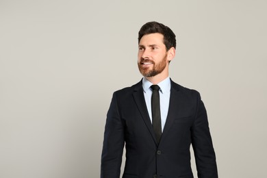 Photo of Handsome real estate agent in nice suit on grey background, space for text