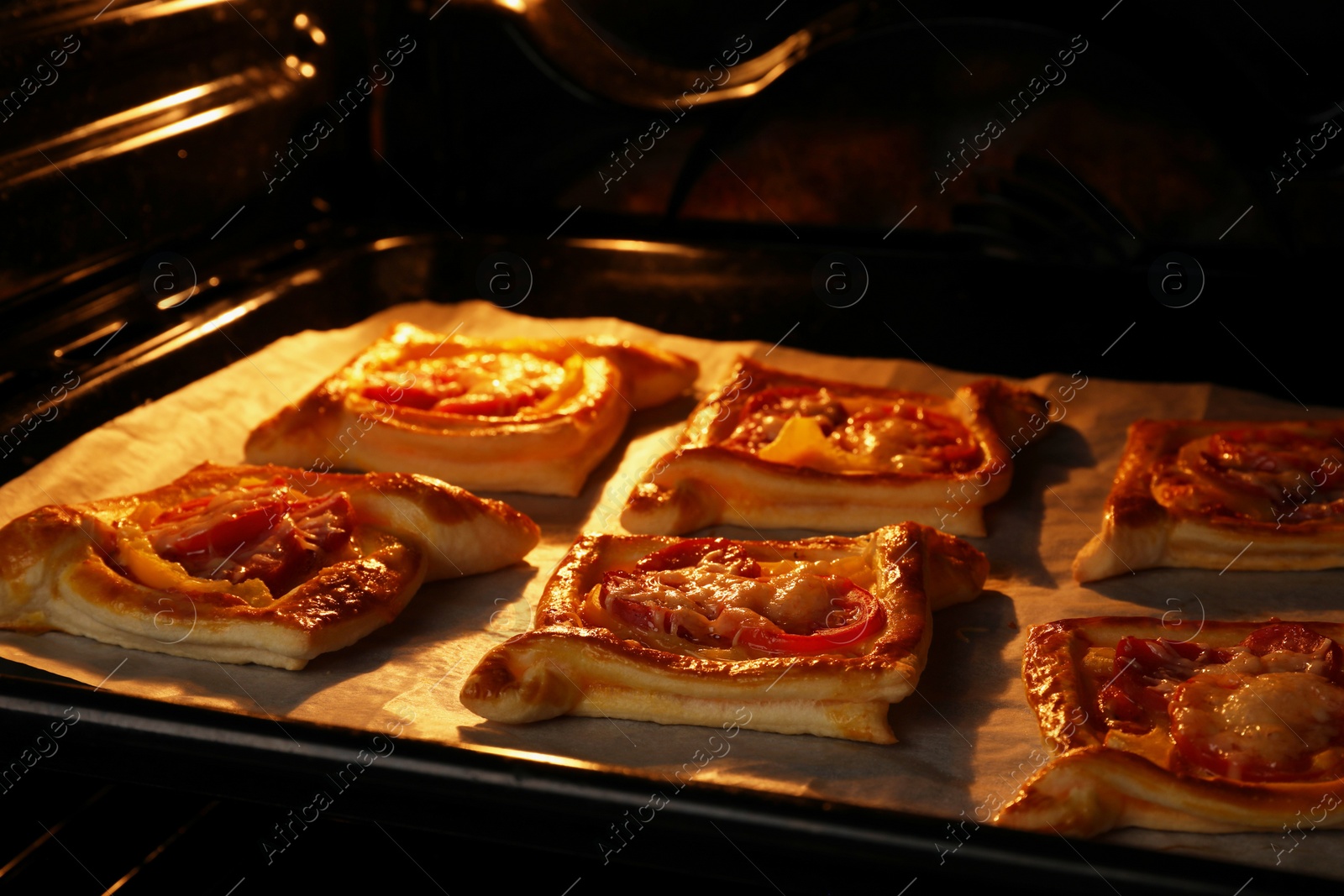 Photo of Baking sheet of puff pastry with tasty filling in oven, closeup