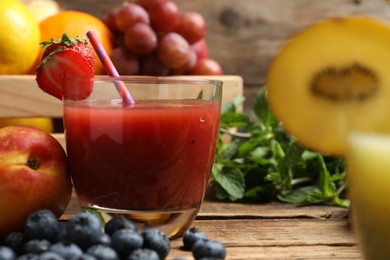 Photo of Delicious colorful juice in glass and fresh ingredients on wooden table, closeup