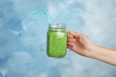 Photo of Woman holding mason jar with delicious smoothie on color background