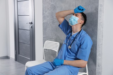 Exhausted doctor sitting on chair in hospital hallway