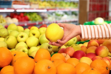 Photo of Woman choosing fruits during shopping in supermarket, closeup