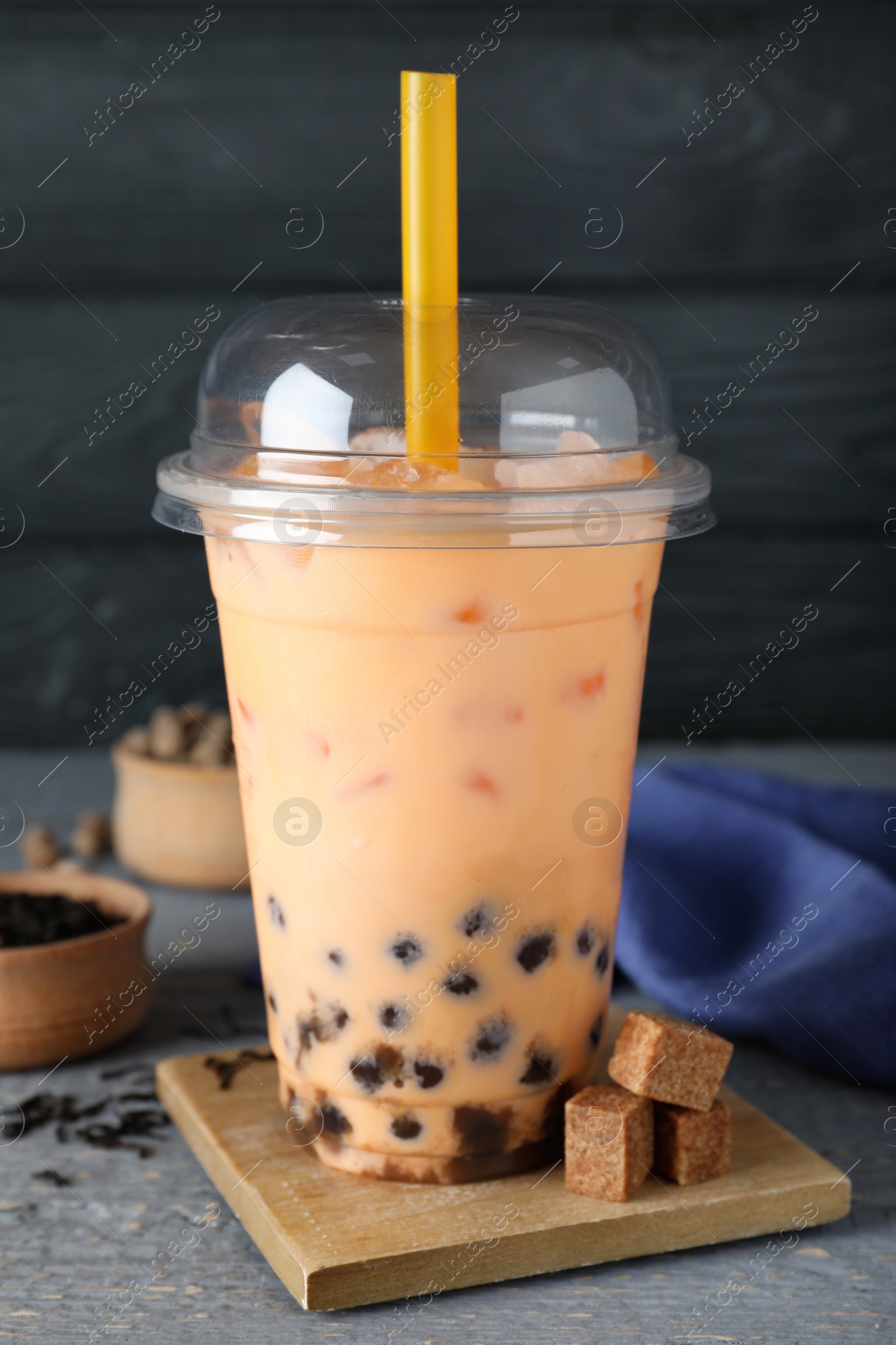 Photo of Tasty brown milk bubble tea in plastic cup on light blue wooden table