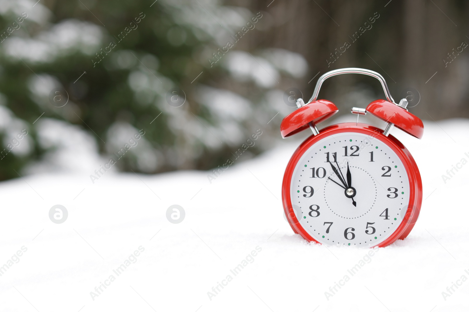 Photo of Red alarm clock on white snow outdoors. Space for text