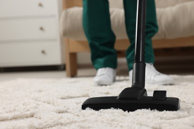 Photo of Dry cleaner's employee hoovering carpet with vacuum cleaner indoors, closeup. Space for text