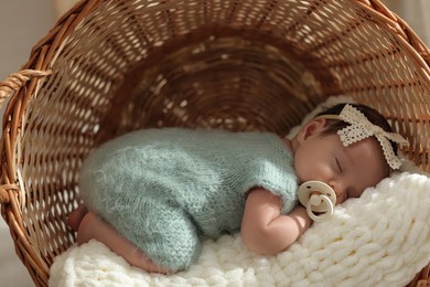 Adorable newborn baby with pacifier sleeping in wicker basket