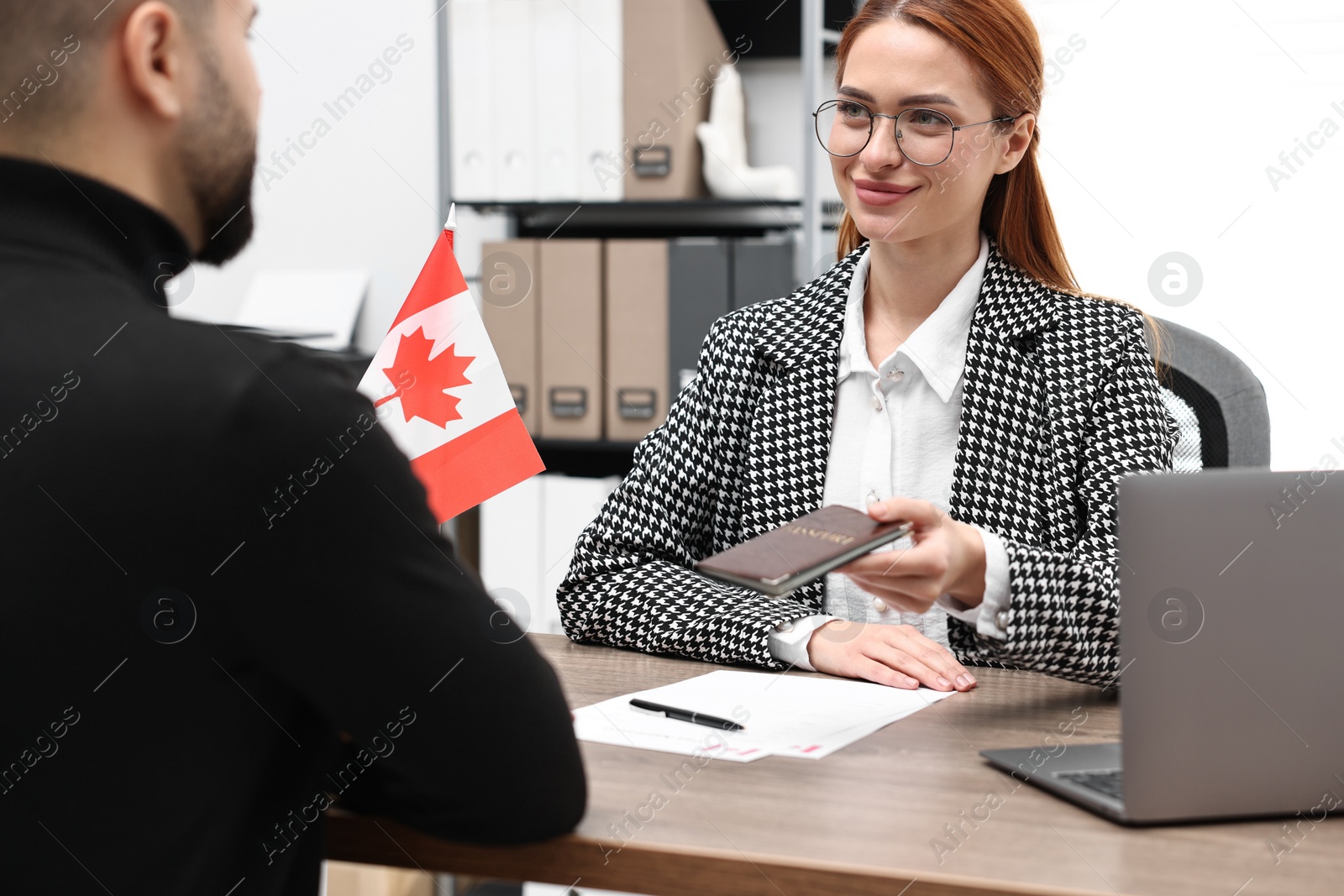 Photo of Immigration to Canada. Embassy worker giving passport to man in office