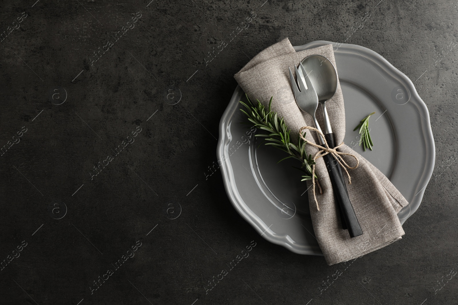 Photo of Stylish setting with cutlery and napkin on black table, top view. Space for text