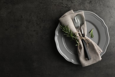 Photo of Stylish setting with cutlery and napkin on black table, top view. Space for text